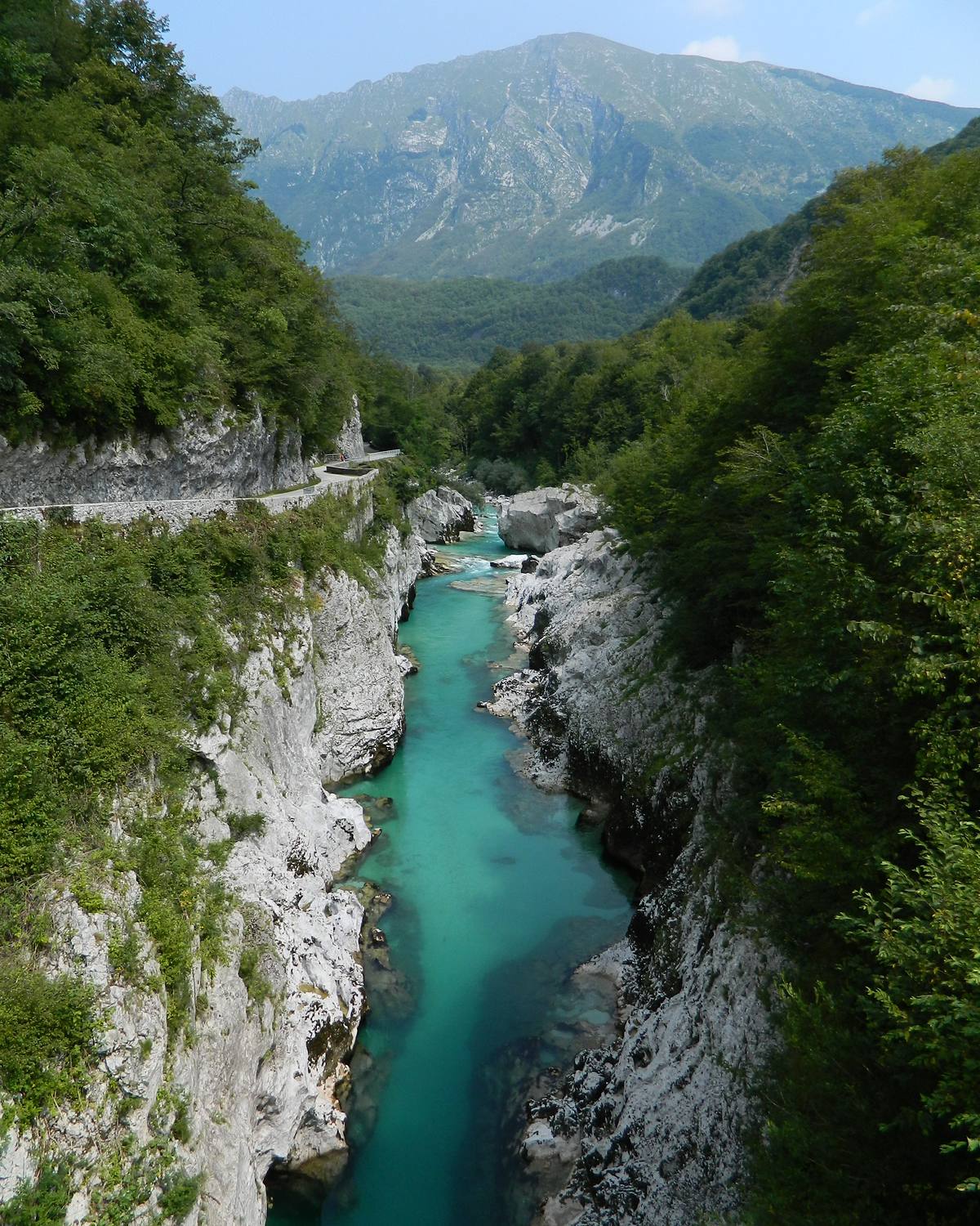 Looking down a narrow limestone gorge at the turquoise river, mountains beyond